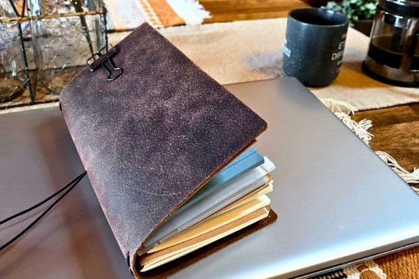 leather travelers journal sitting on a laptop.