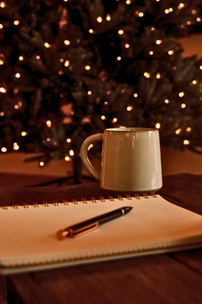 christmas tree in the background and a notebook on the table with a cup of coffee