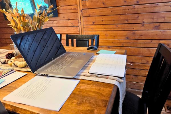 a laptop on a kitchen table with a planner for setting priorities