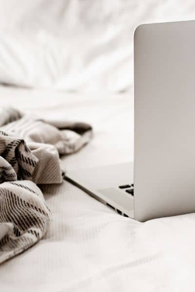 laptop on a bed with a cozy blanket a cozy space for learning how to set priorities