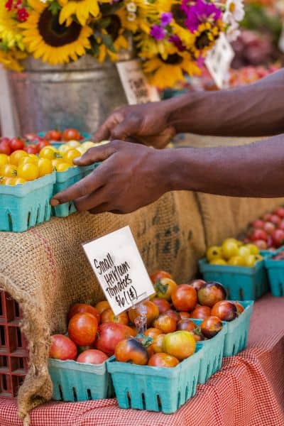man picking up tomatoes at a farmers market