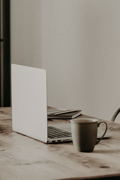 laptop on a rustic dinner table with a cup of coffee